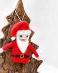 Felt Santa Claus ornament hanging on a wooden tree branch against a white background
