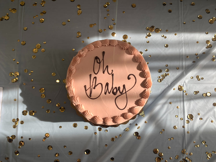 Confetti surrounding a pink cake for a baby shower