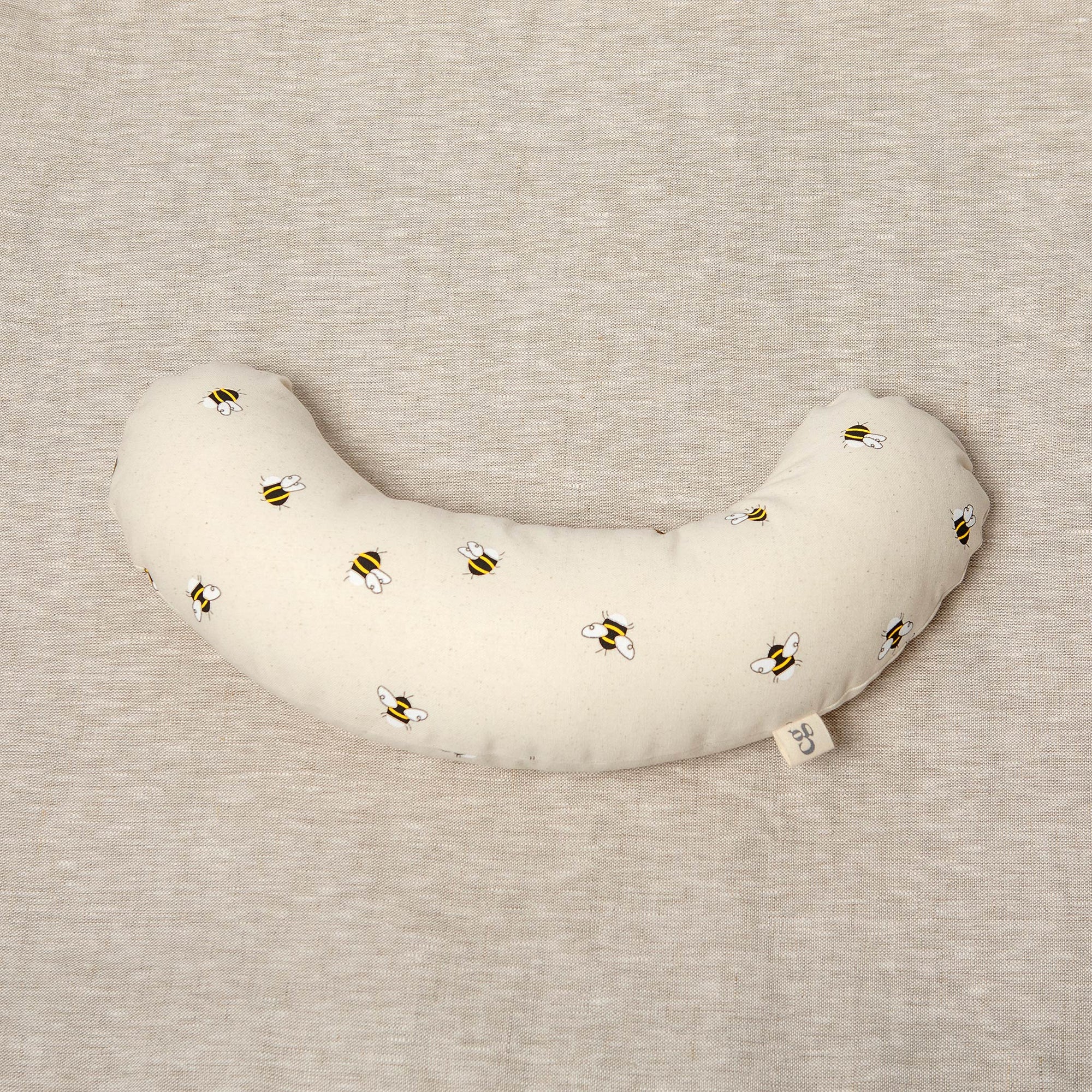 The Bee tummy time support aid helps newborn babies during their floor time. Made from a supportive wooden lining and a washable cotton cover. The fabric print has bees printed on it.