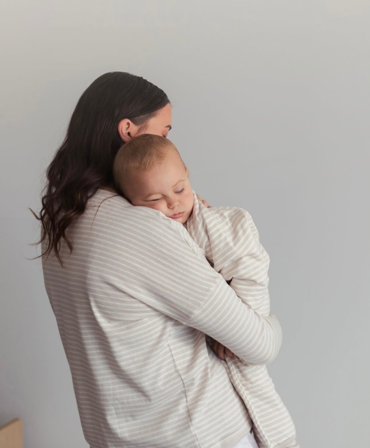 New Zealand Mother holding a baby wrapped in Woolbabe Sleep Pj Suit and Baby Blanket 